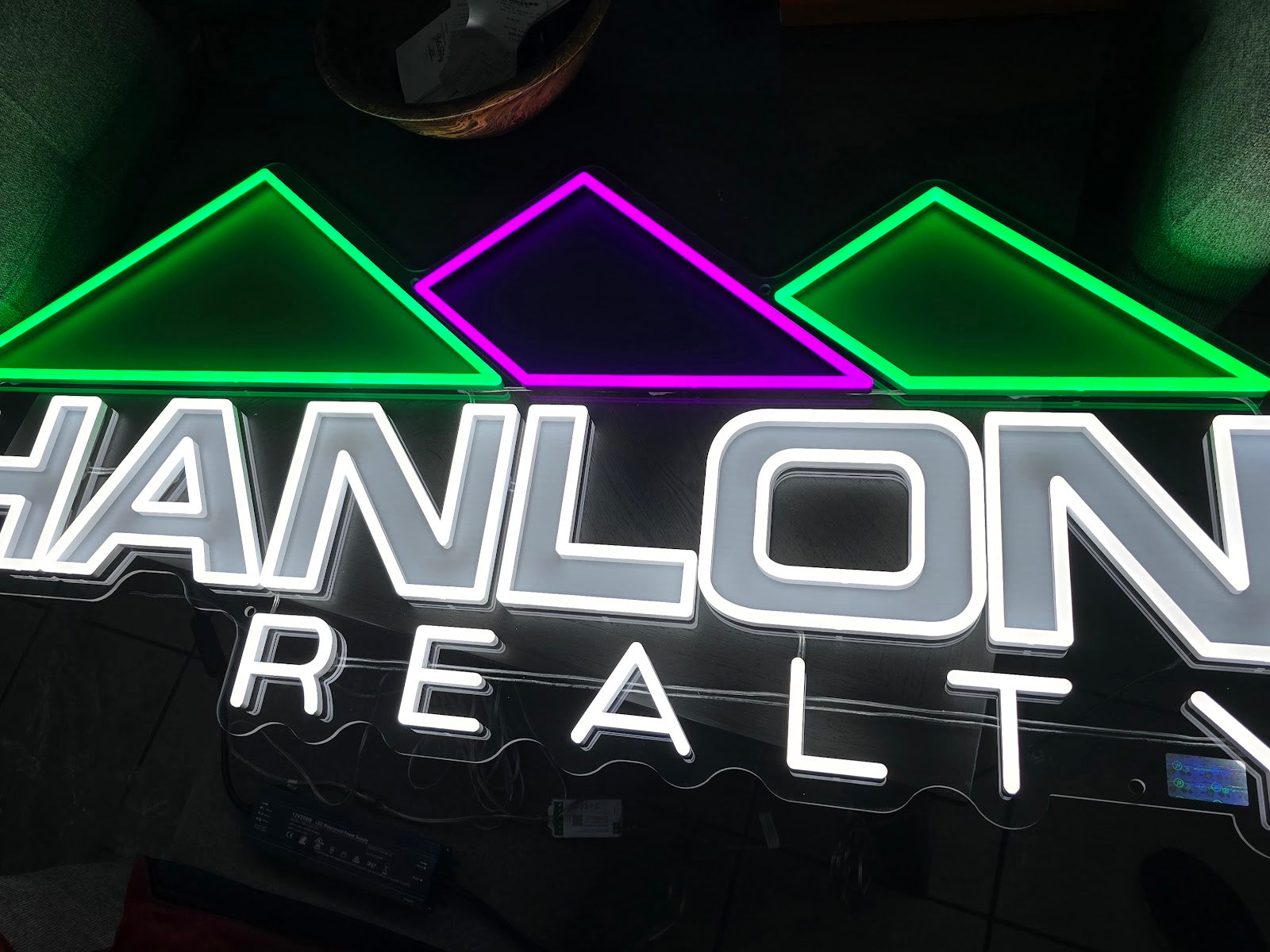 Hanlon Realty neon sign illuminated in the customer photo