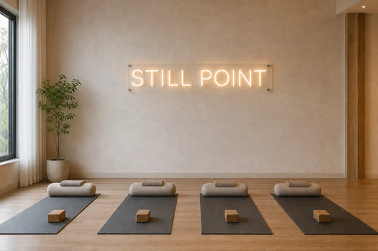 Concept rendering of a calm yoga studio with a warm-white STILL POINT LED neon sign above neatly arranged mats