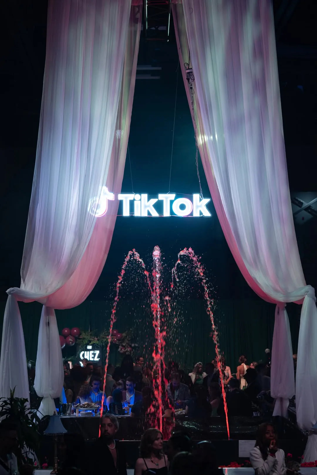 White TikTok LED neon logo hanging above a branded indoor corporate event