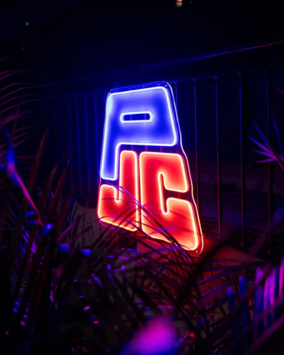 Red and blue custom logo LED neon sign glowing in a dark business venue