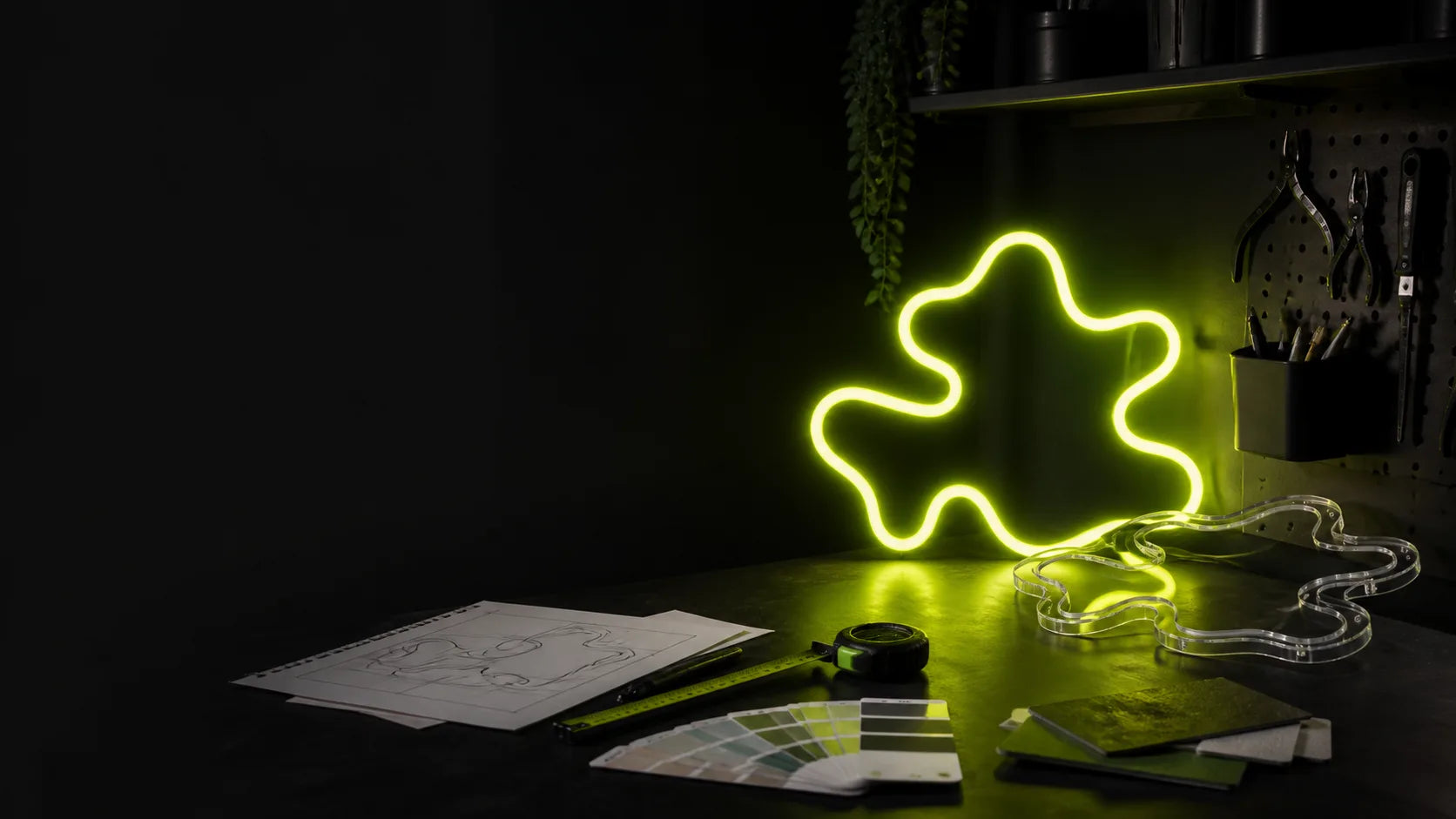 LED neon sign planning desk with sketch, measurements and finished abstract sign
