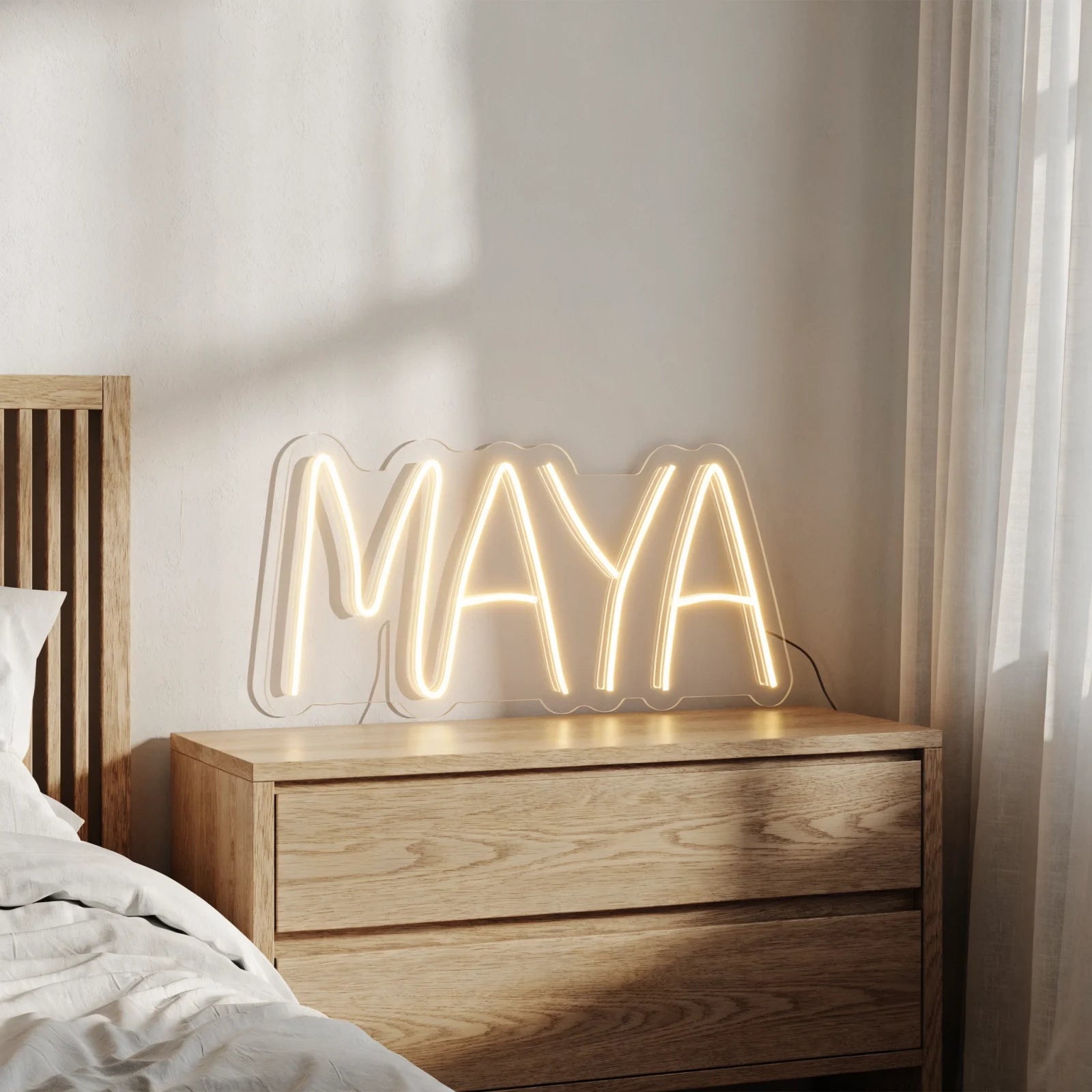 Warm white MAYA neon name sign on clear acrylic in a bedroom